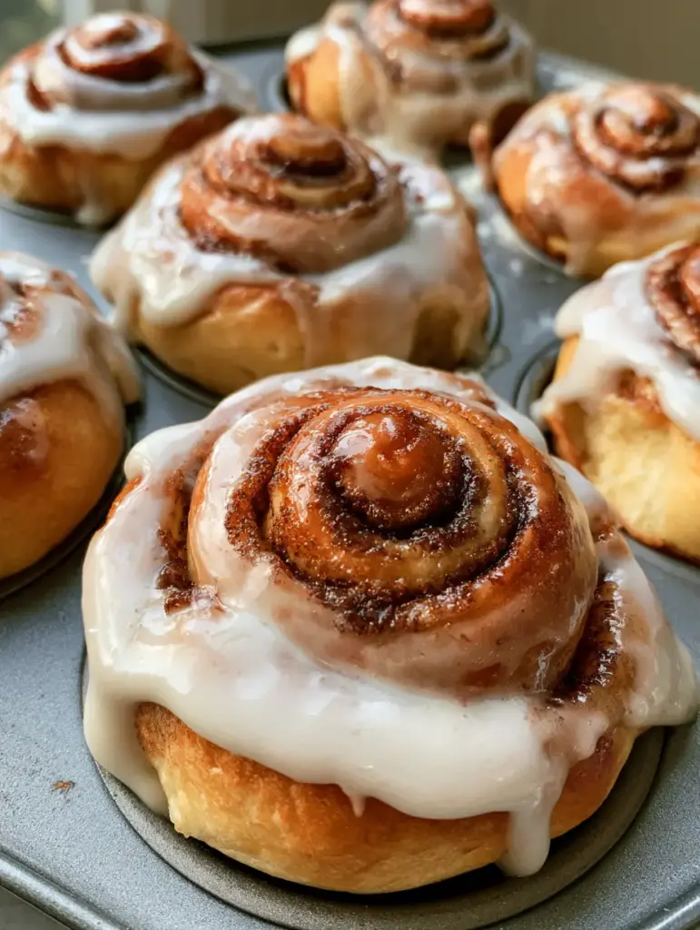 Cinnamon Roll Muffins: The Ultimate Fluffy Bakery-Style Recipe 1 Close up of soft and pillowy Cinnamon Roll Muffins inside a grey metal muffin tin.