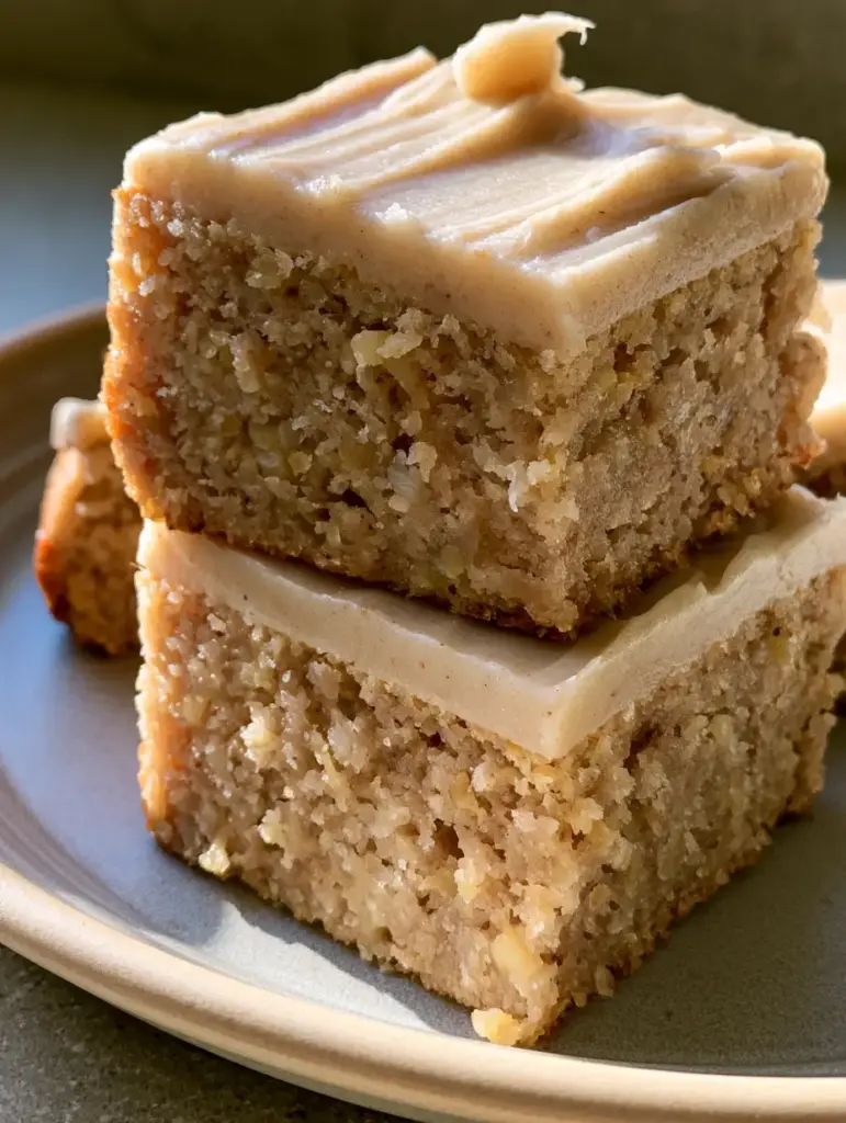 Handheld photo of a thick Banana Bread Brownie square on a ceramic plate in natural daylight.